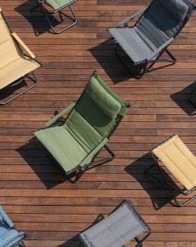 Dette er et bilde av sammenleggbare stoler plassert på en terrasse med tredekke. Stolene er av ulike modeller og farger.