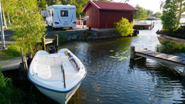 Bilde tatt i dagslys som viser en fredelig og idyllisk scene ved en vannkant, sannsynligvis en elv eller en kanal.